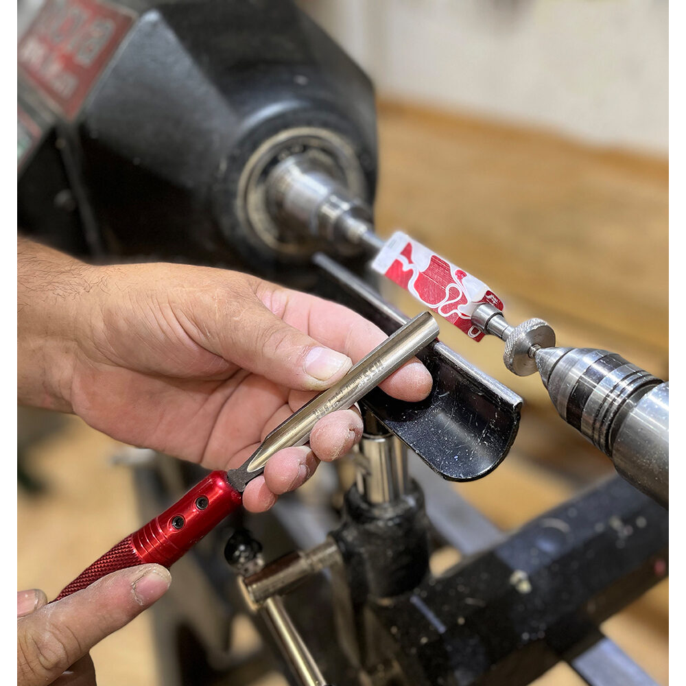 Hand using red and steel tool to shape resin pen blank on lathe in woodworking tools under $100 collection