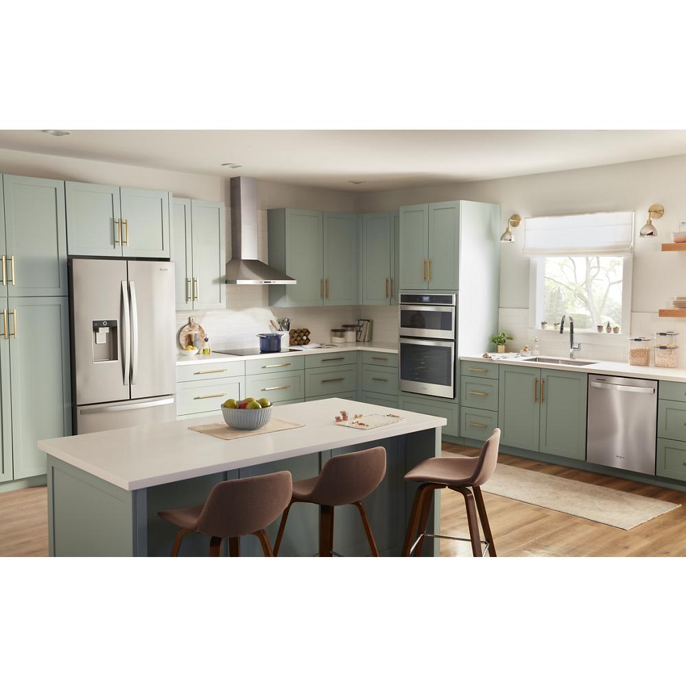 Modern kitchen with stainless steel chimney range hood, light green cabinetry, and spacious island with seating