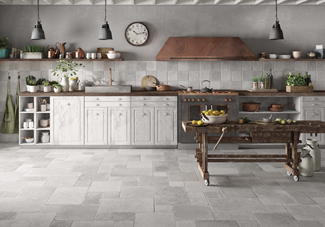 Rustic kitchen with matte stone-look tile flooring and backsplash, featuring white cabinetry and wooden accents for home improvement.