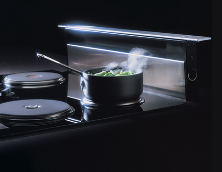 Stainless steel downdraft vent with top cover installed behind a cooktop in kitchen appliances and home improvement collections