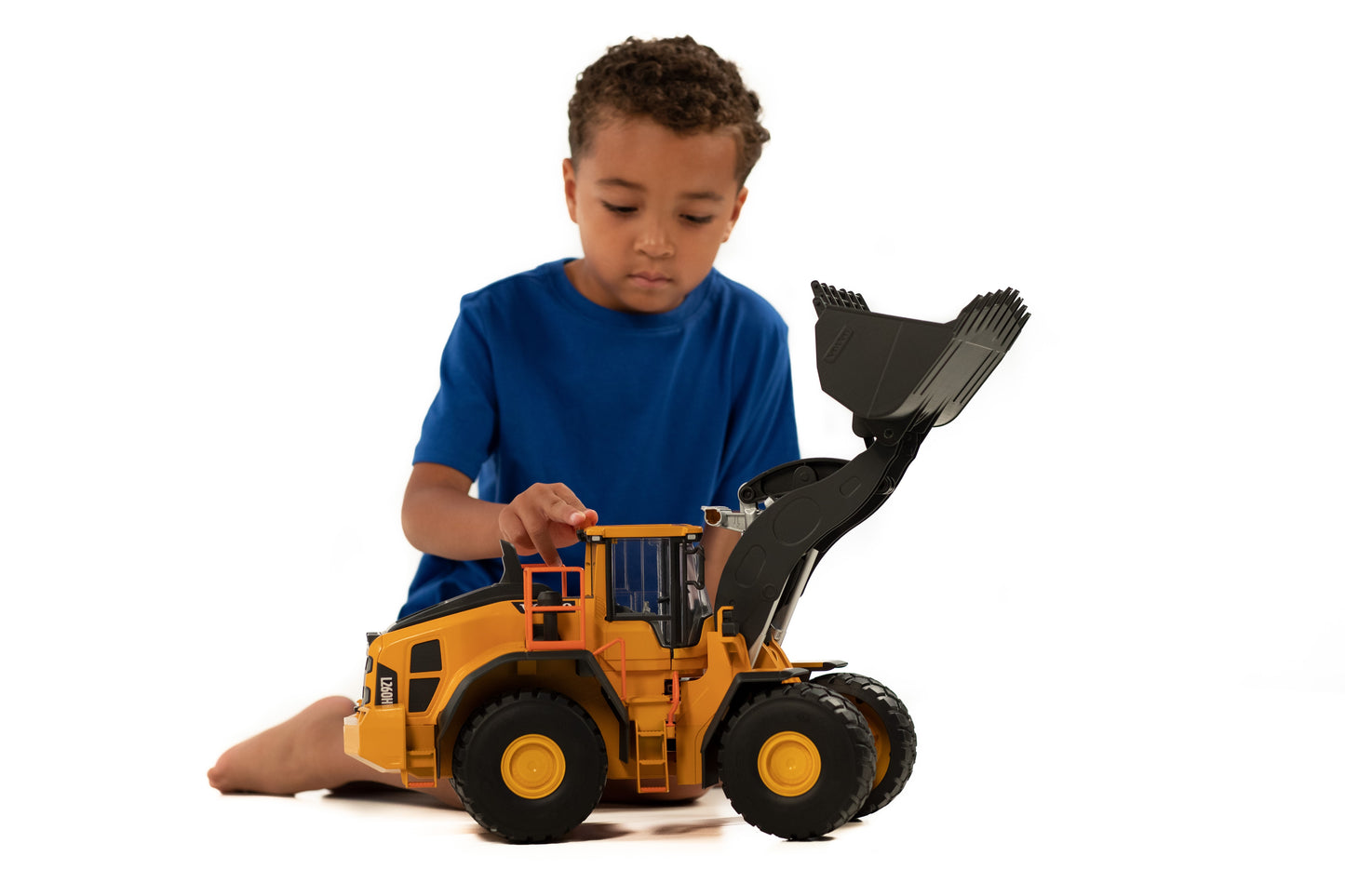 Child playing with detailed yellow Bruder Volvo wheel loader toy featuring movable bucket and black tires for construction play