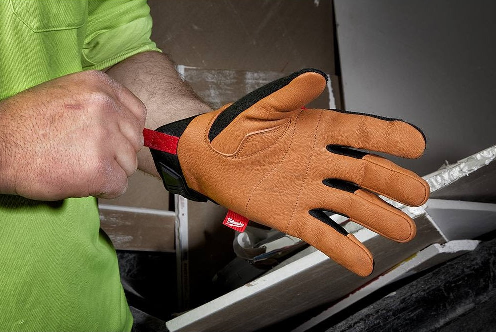 Hand slipping on a Milwaukee XL leather performance glove with a red pull tab for home improvement tasks