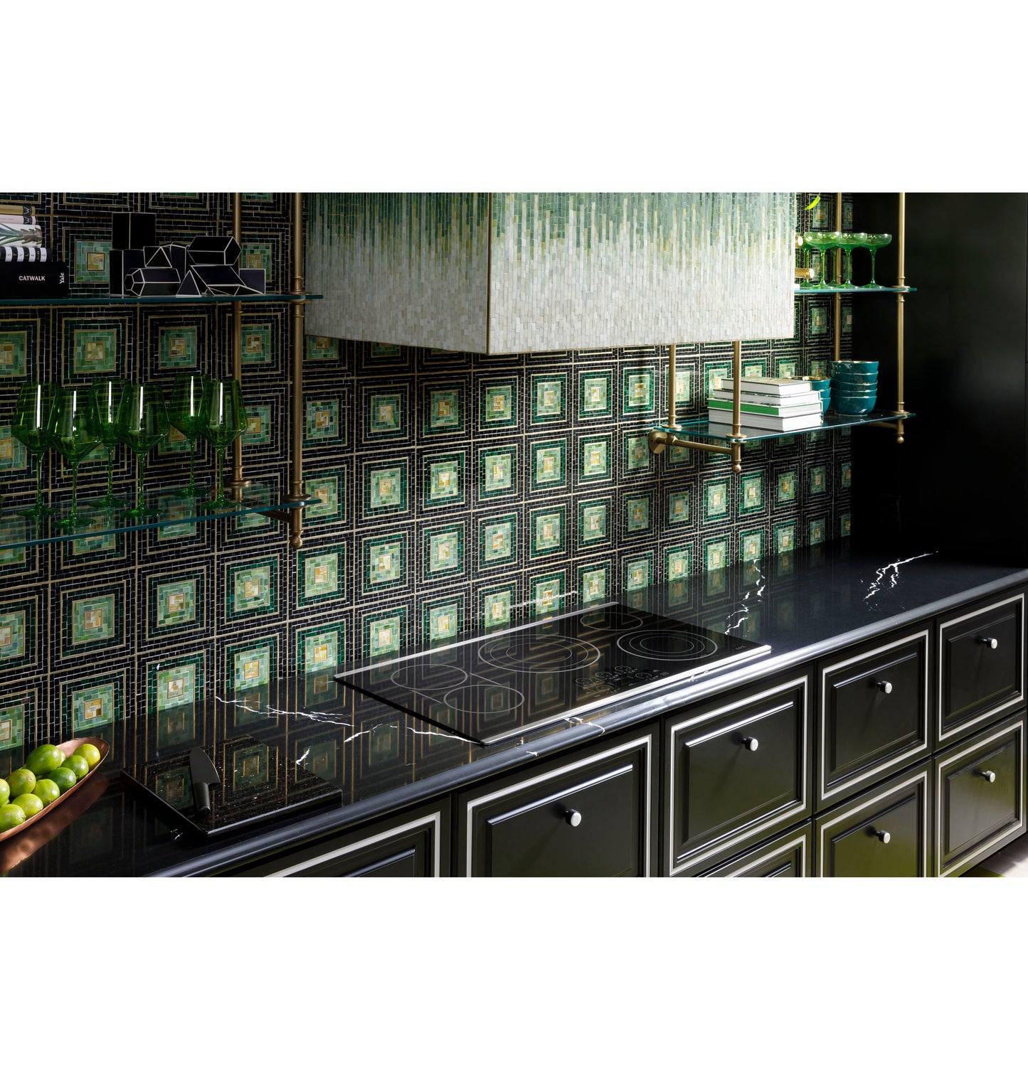 Black glass 36-inch electric cooktop with touch controls integrated into black cabinetry under patterned green tile backsplash in kitchen