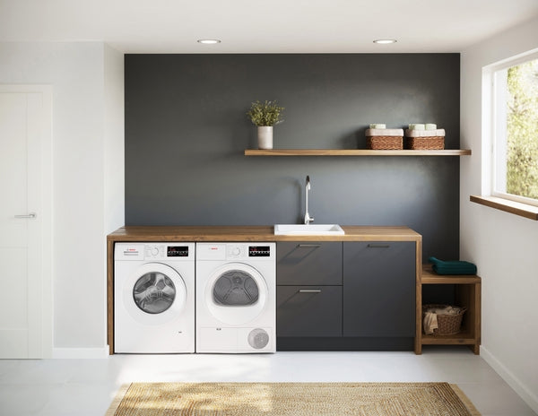 Minimalist laundry room with white front-loading washer and dryer under natural wood countertop and gray cabinetry