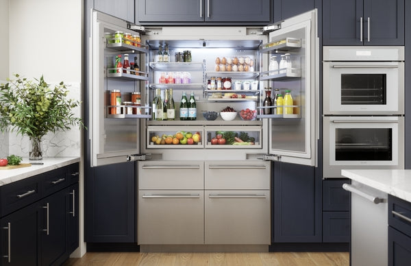Built-in stainless steel French door refrigerator open to show organized shelves with fruits, beverages, and eggs in modern kitchen