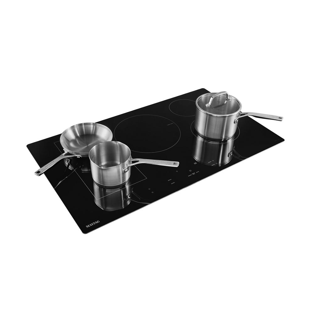 36-inch wide black induction cooktop with stainless steel pots and touch controls in kitchen appliance setting
