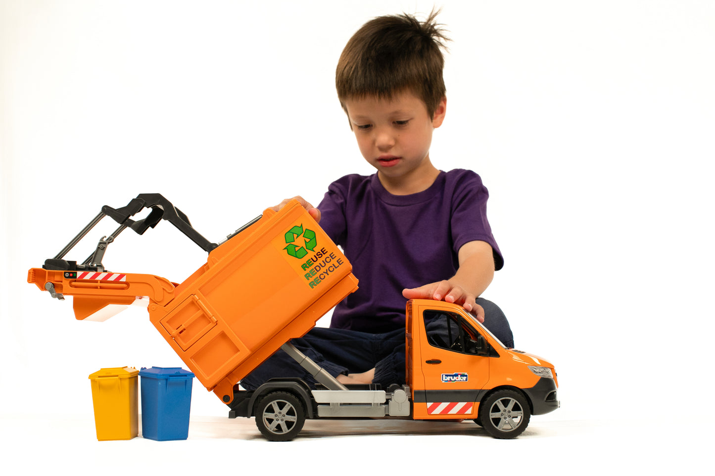 Child playing with orange toy garbage truck and colorful recycling bins in a home improvement setting