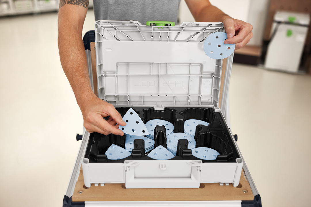 Person organizing blue sanding discs inside gray tool case for power tool accessories and sanding supplies collections under $100