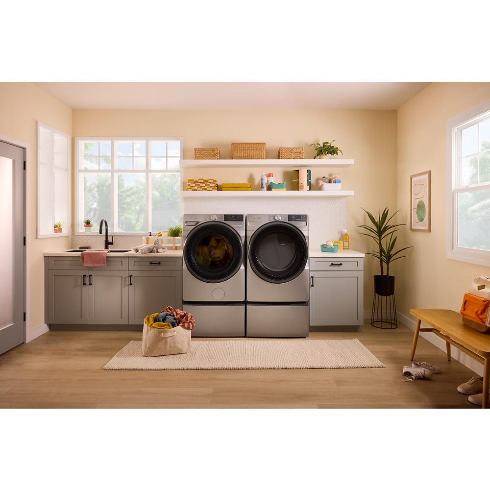 Front load smart electric washer and dryer in brushed steel with digital controls in a bright laundry room setting