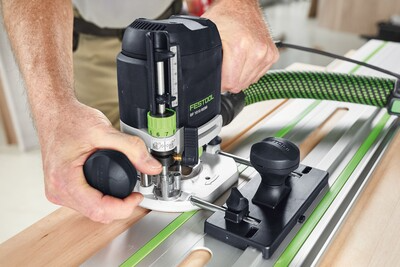 Hands operating a Festool plunge router on wood using a guide rail for accurate woodworking and power tool accessories