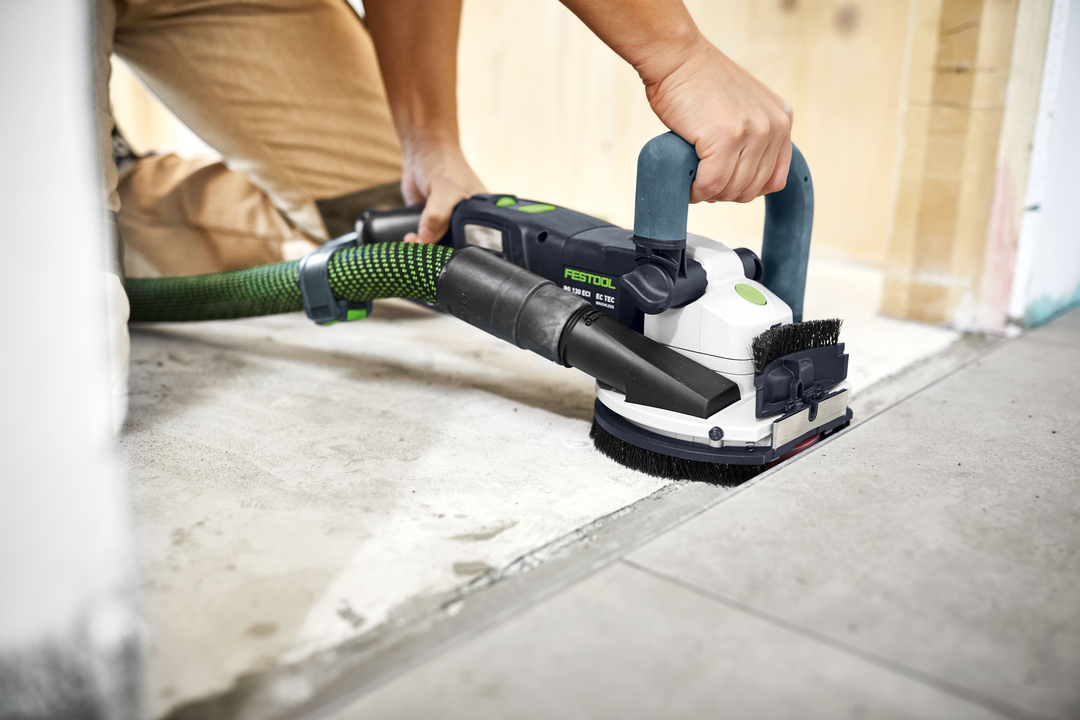 Person using Festool diamond grinder with dust extraction smoothing concrete floor for home improvement tasks