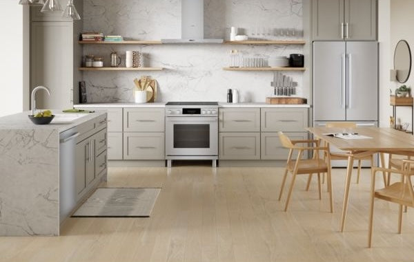 Bright kitchen with stainless steel induction range, marble countertops, light gray cabinets, and wooden dining set from Bosch collection