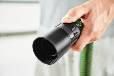 Hand holding green and black anti-static extractor hose connector for woodworking dust collection tools and shop vacuums