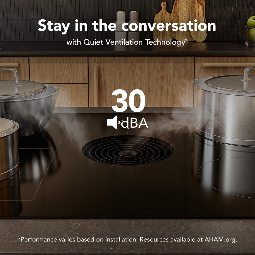 Black induction cooktop with quiet downdraft ventilation at 30 decibels in modern kitchen setting with cookware