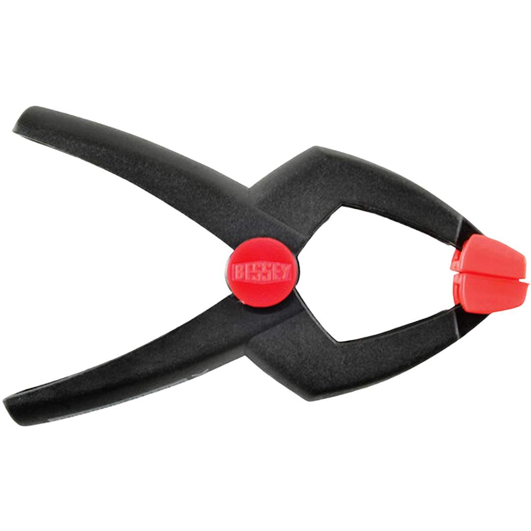 Black spring clamp with red tipped jaws and ergonomic handles for precise holding in home improvement projects