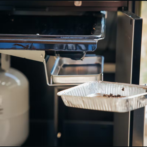 Removable grease tray and disposable drip pan under stainless steel natural gas grill for outdoor cooking and grilling