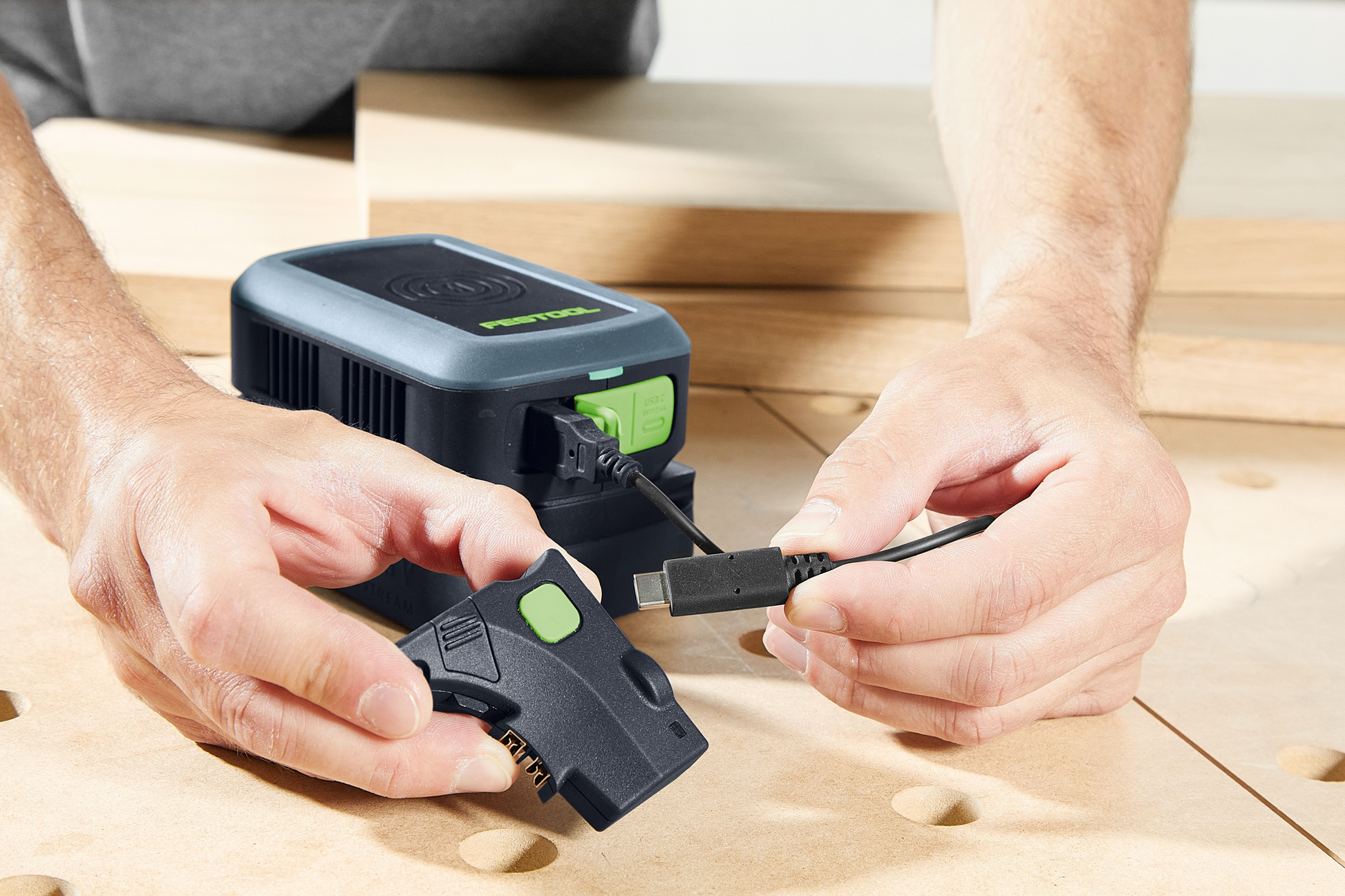 Hands connecting a Festool light module with battery on a woodworking bench, Home Improvement tools setup