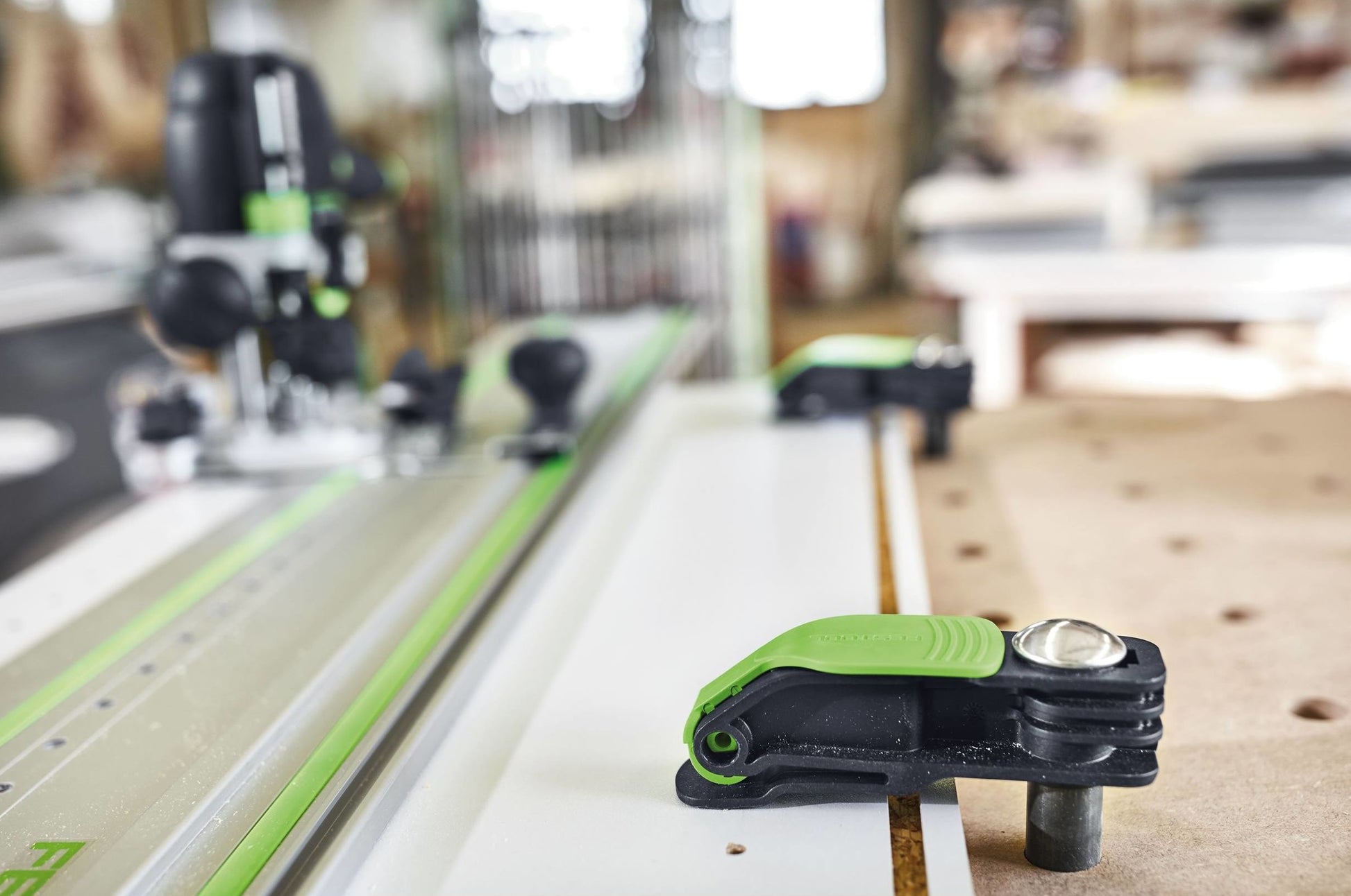 Green and black Festool quick clamp attached to a woodworking table for precise tool and home improvement tasks
