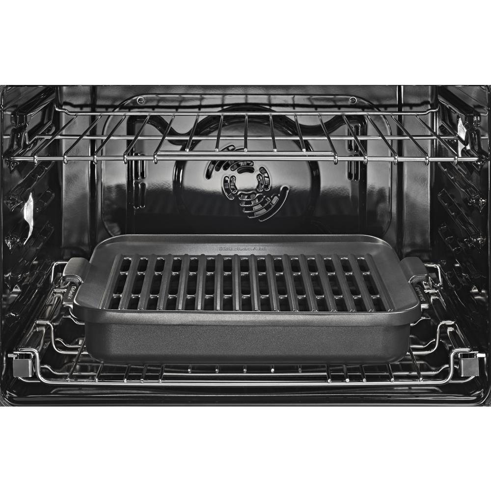 Interior view of stainless steel wall oven with removable grill pan attachment on middle rack in kitchen setting