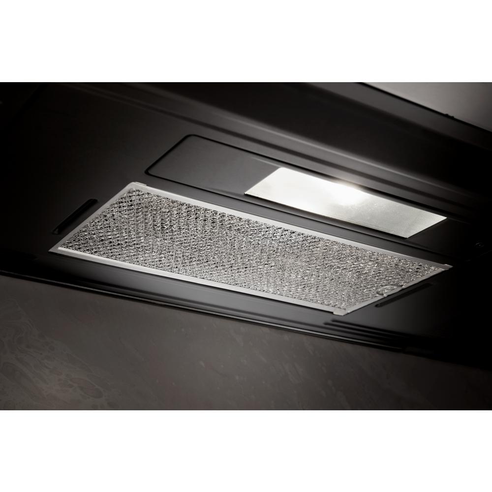 Close-up of metallic mesh vent filter and rectangular light panel on underside of kitchen over-the-range microwave