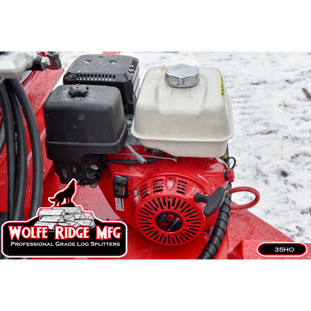 Close-up of red commercial log splitter engine and fuel tank outdoors on snowy ground in firewood processing area
