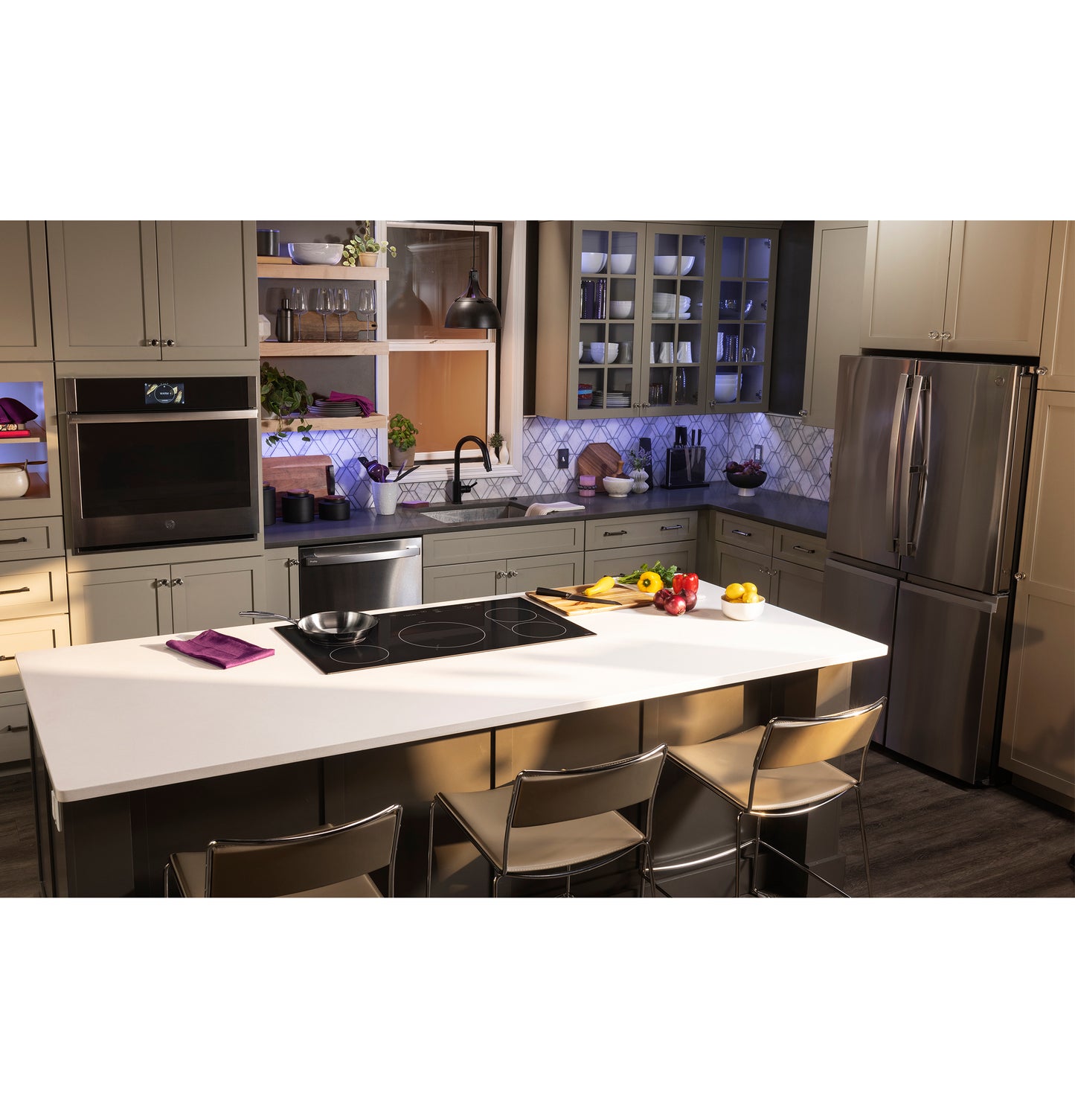 Modern kitchen island with built-in black induction cooktop, stainless steel appliances, and beige cabinetry in home improvement setting