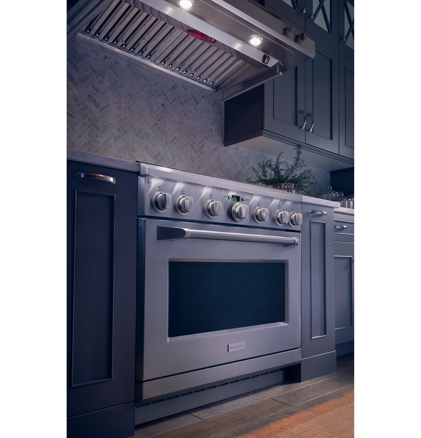 Modern kitchen with stainless steel range and professional hood above dark cabinetry and tiled backsplash