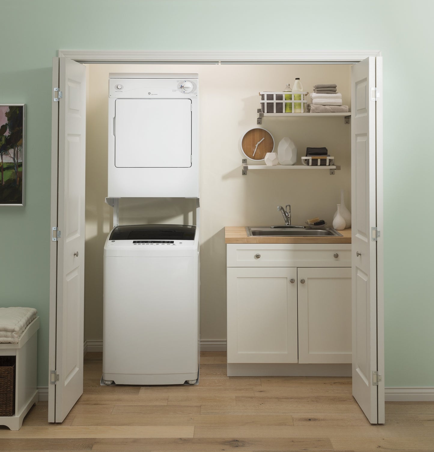 Compact laundry nook with stacked white electric dryer and washer beside a sink and wooden countertop in appliances collection