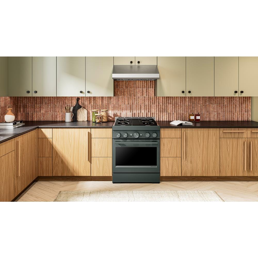 Contemporary kitchen with a dark green 30-inch commercial-style gas range set amidst wood and cream cabinets and black countertops