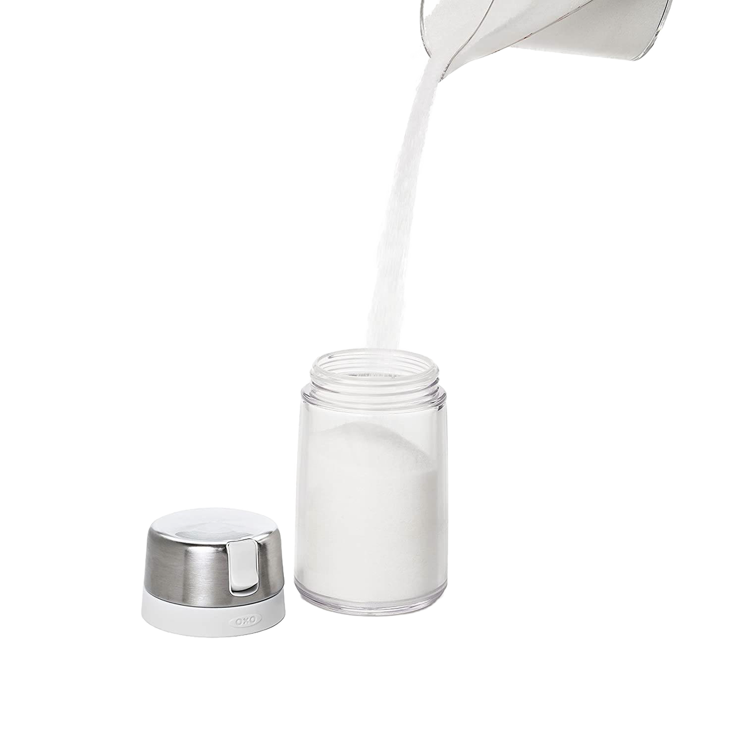 Clear OXO sugar dispenser with stainless steel lid and white spout with sugar pouring into container for kitchen storage