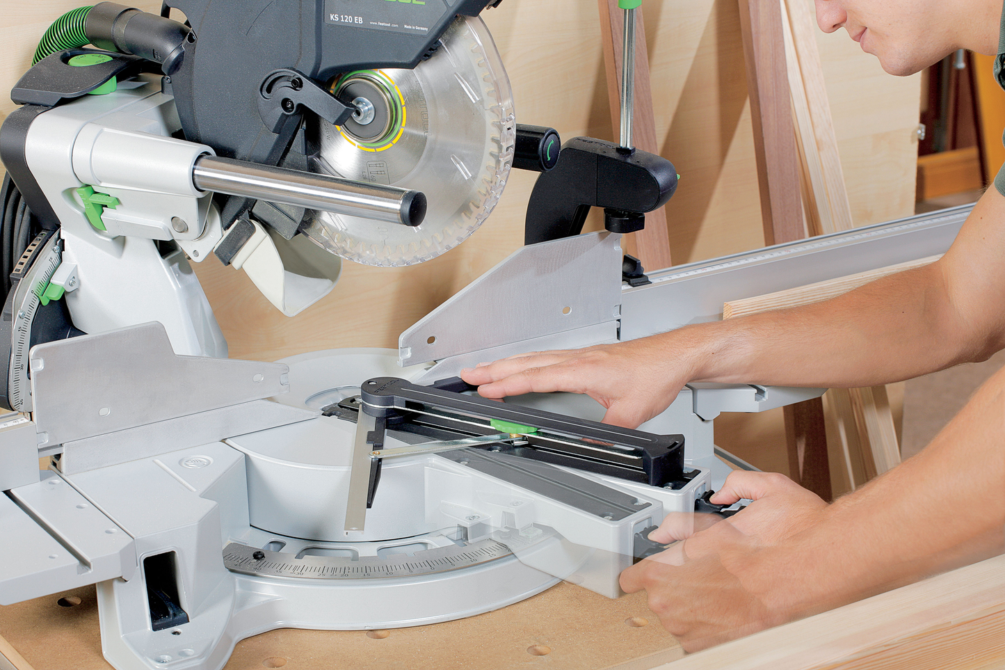 Worker adjusting sliding compound miter saw for precise angled cuts in power tools and home improvement collections