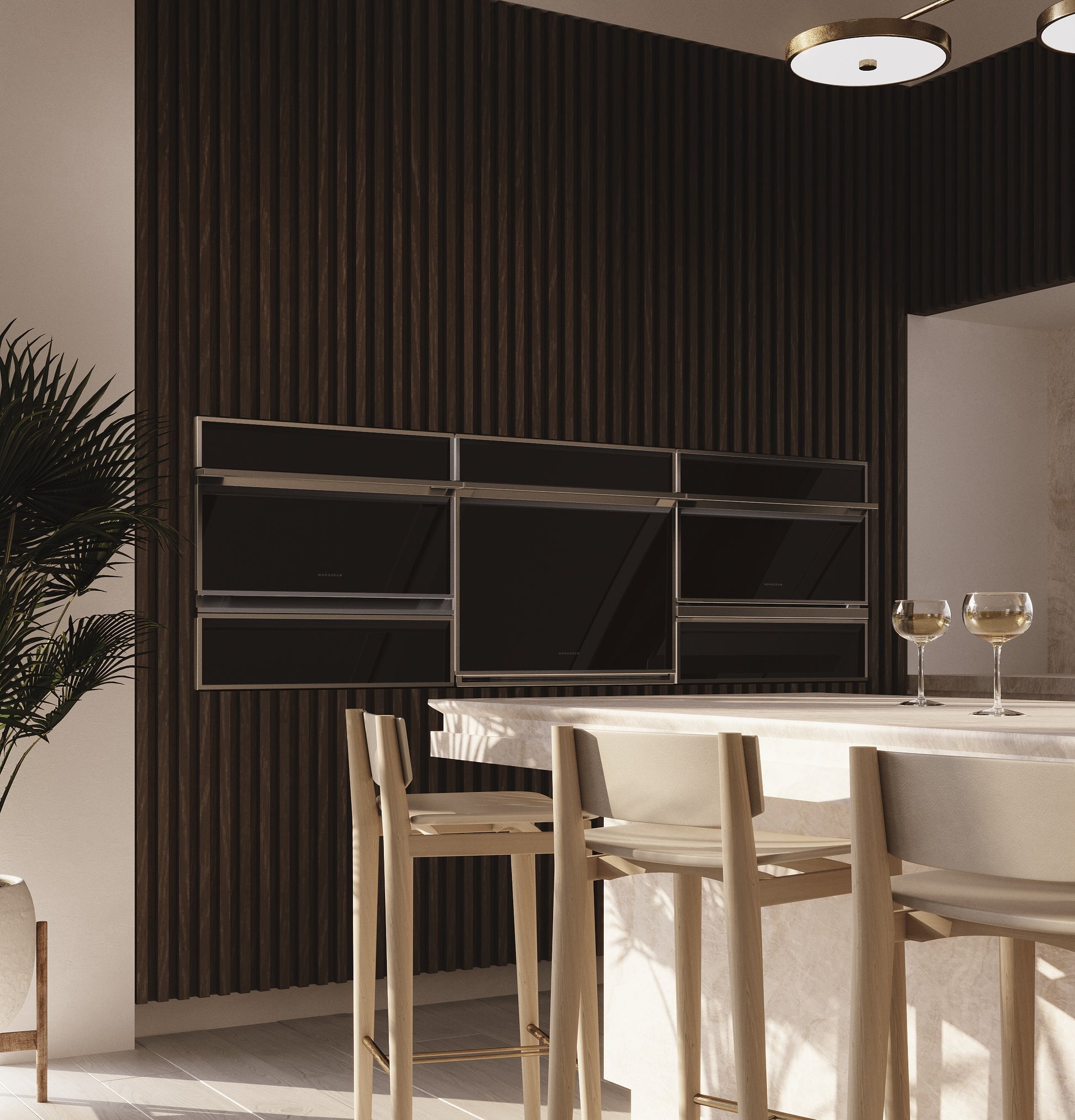 Modern kitchen setup featuring built-in minimalist warming drawer and wall ovens in a contemporary space with bar stools and ambient lighting