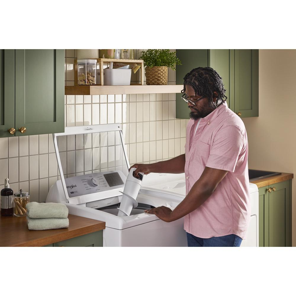 Man in pink shirt loading white top load washer with 2-in-1 removable agitator in green kitchen setting