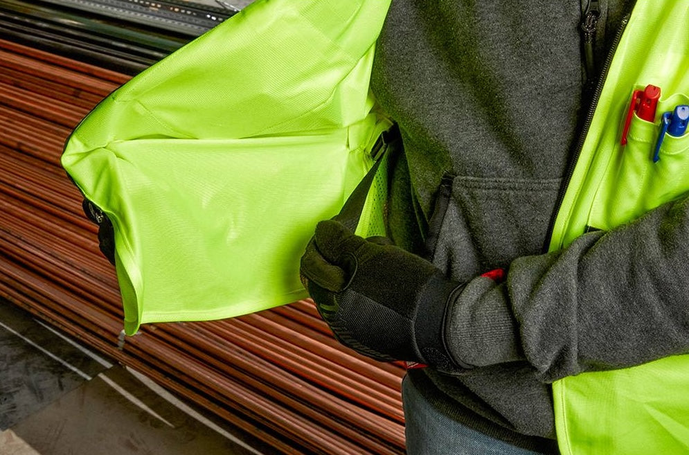 High visibility yellow Milwaukee vest with zippered interior pocket worn over gray sweatshirt for tools and home improvement tasks