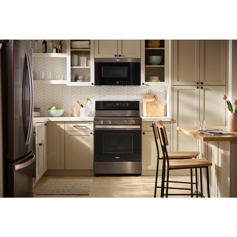 Bright kitchen with beige cabinets featuring flush built-in black air fry microwave above matching freestanding oven and dining area