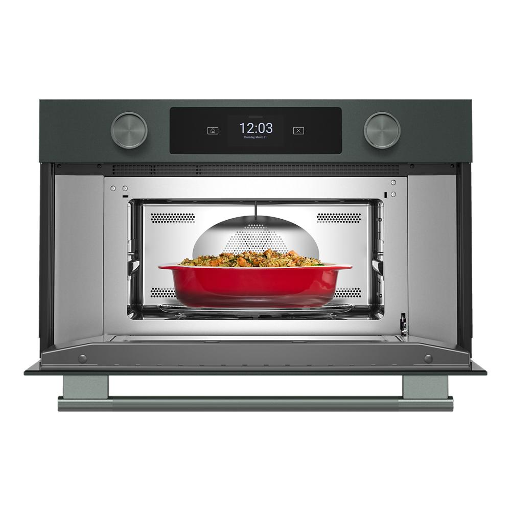 Built-in gray microwave oven with digital display, control knobs, and red ceramic dish cooking inside from KitchenAid collection
