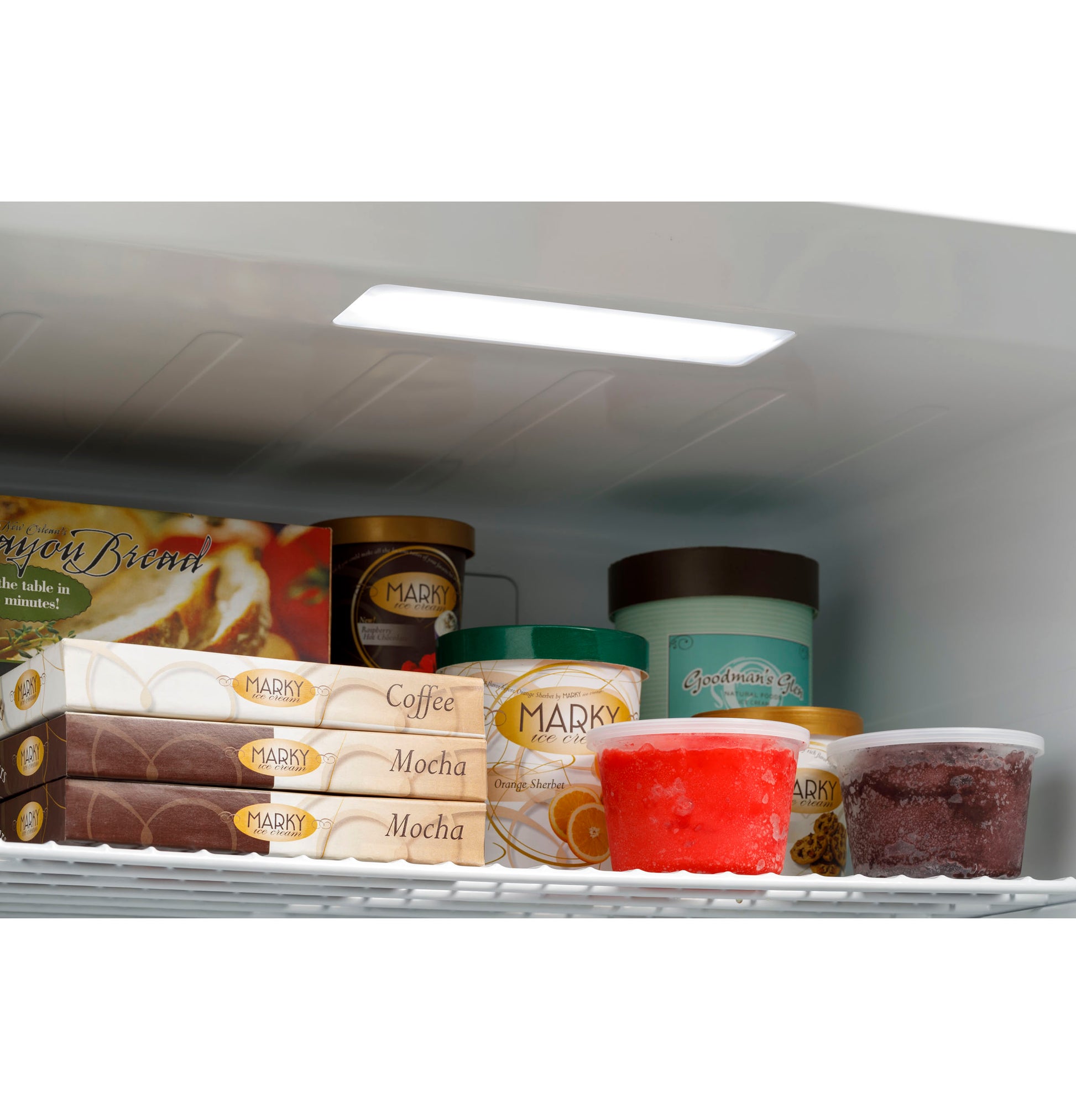 Interior view of upright freezer shelf with assorted frozen desserts and ice cream containers in freezer collection