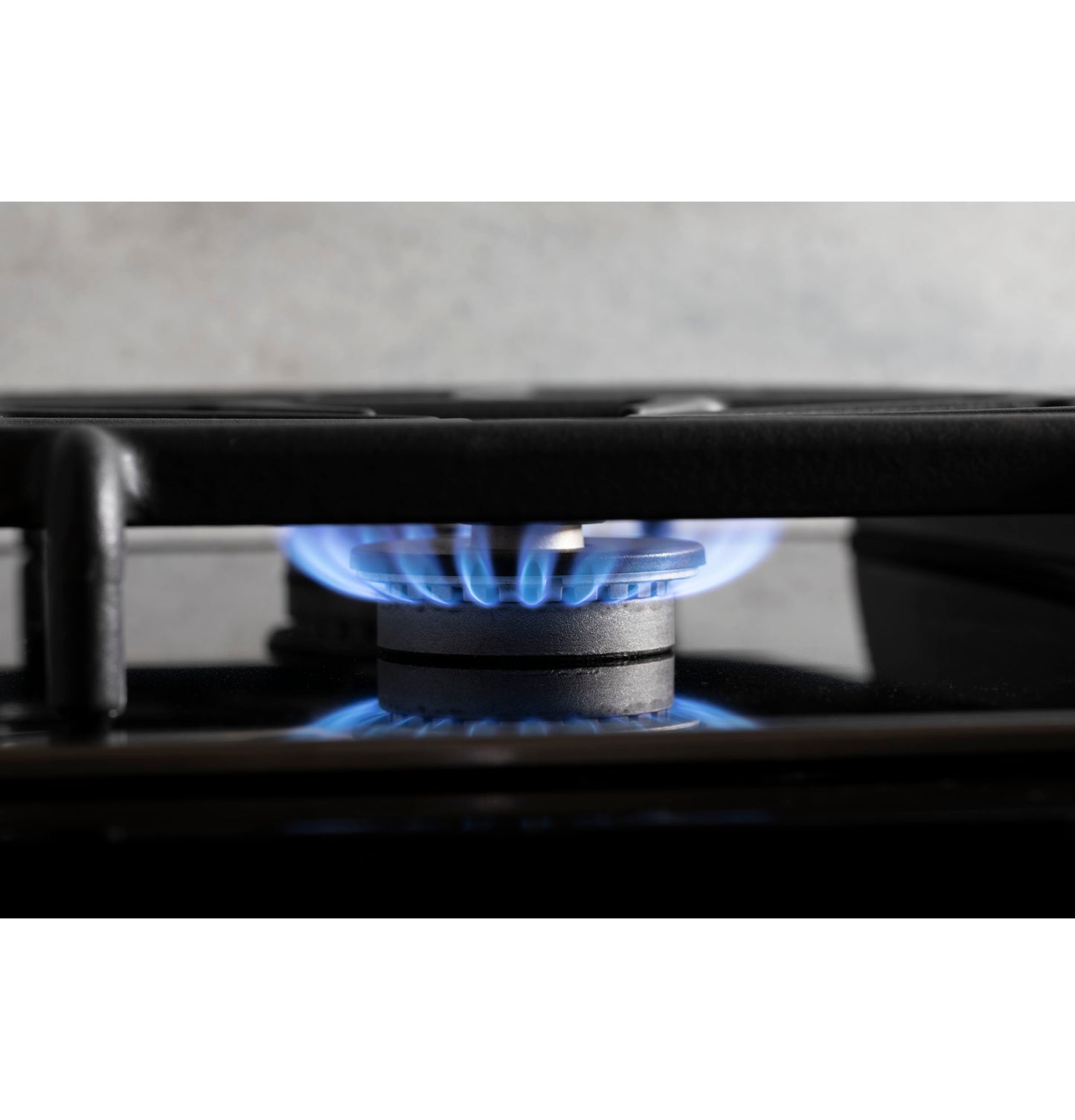 Blue flame burning on black gas burner of built-in cooktop in modern kitchen setting for home improvement