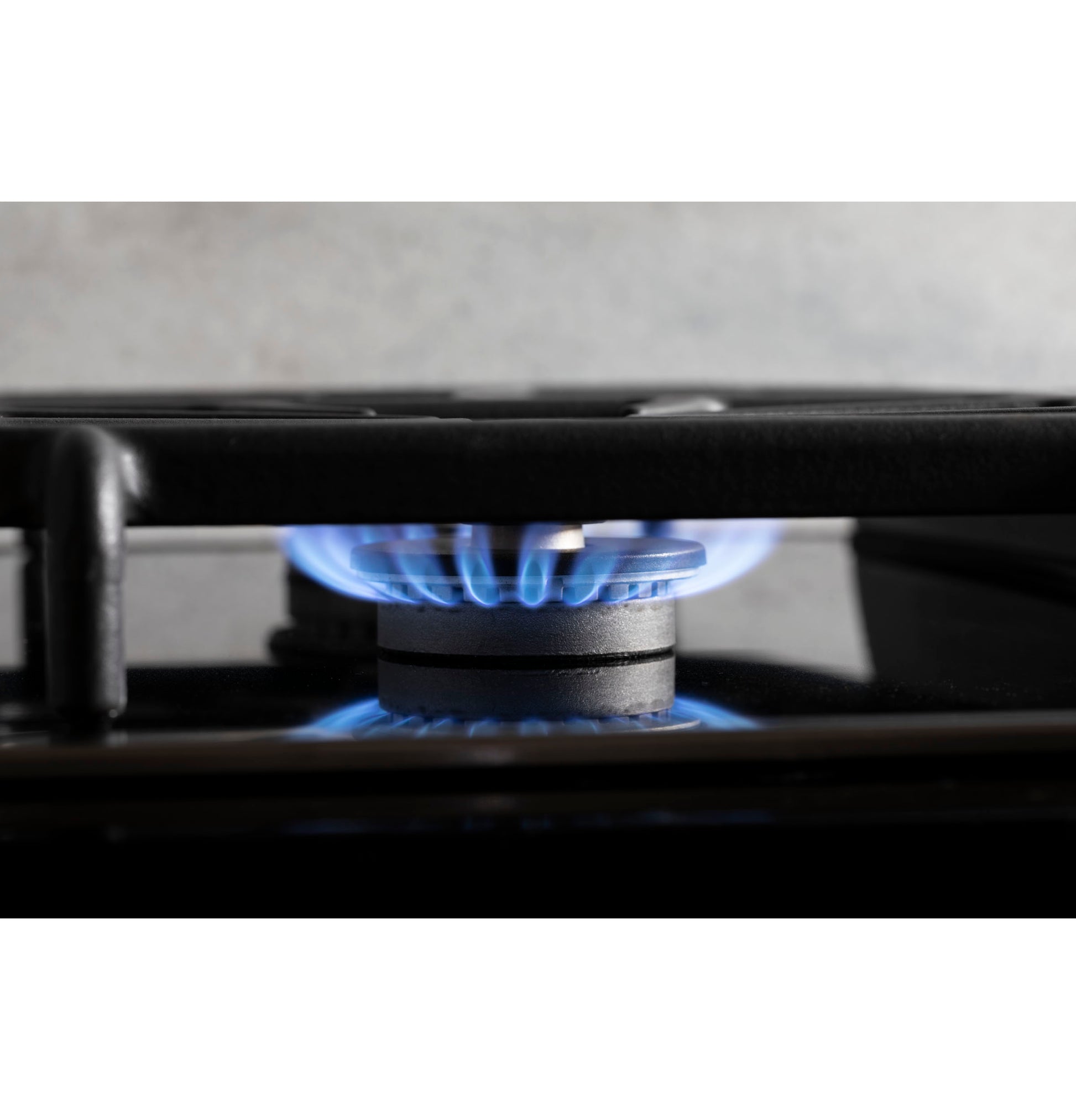 Blue flame burning on black gas burner of built-in cooktop in modern kitchen setting for home improvement