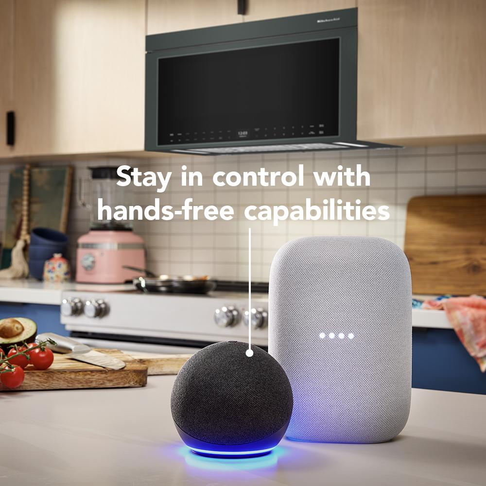 Modern kitchen scene with black multifunction microwave mounted above stove and smart speakers on countertop