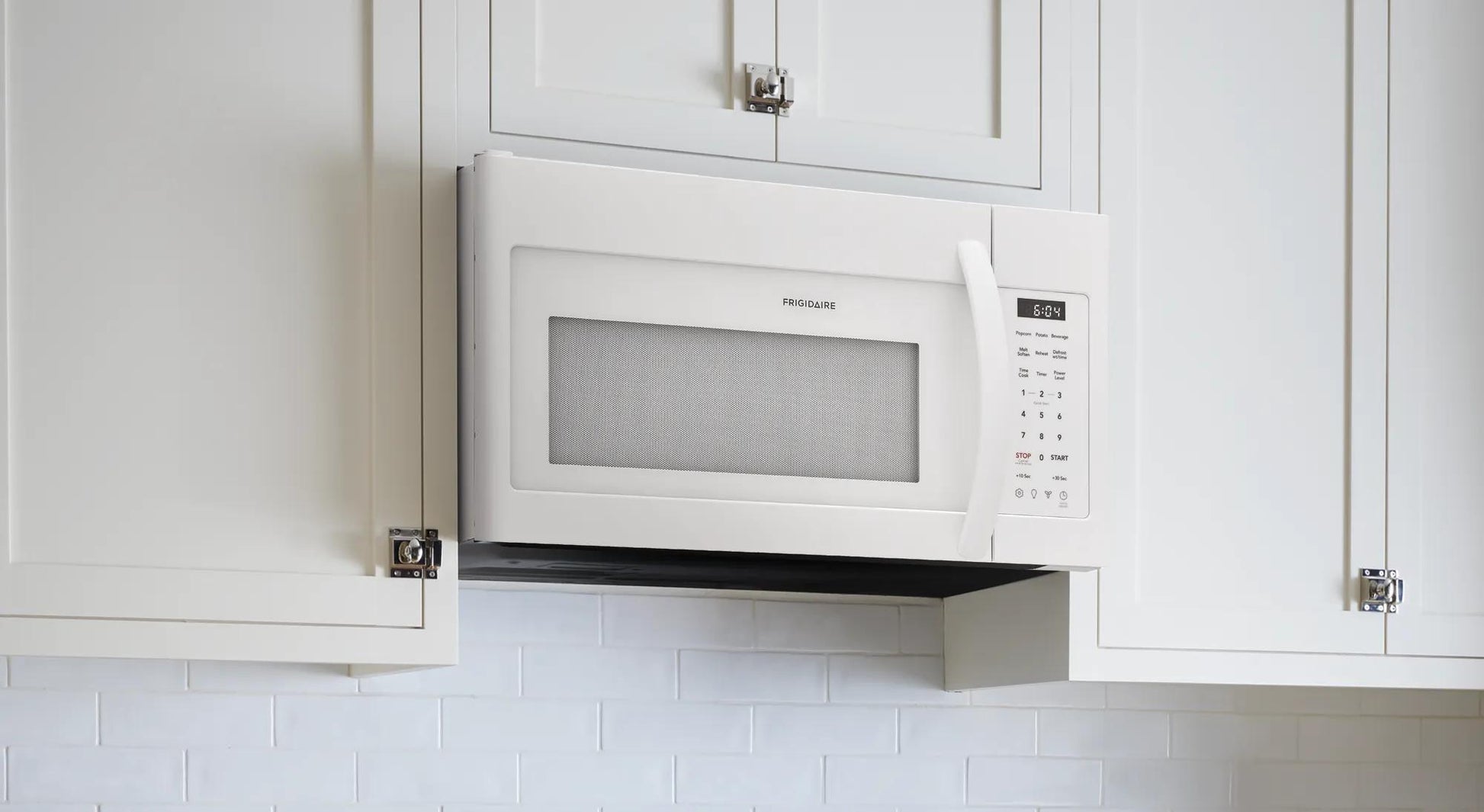 White over-the-range microwave installed above stove with digital touch control in modern kitchen setting