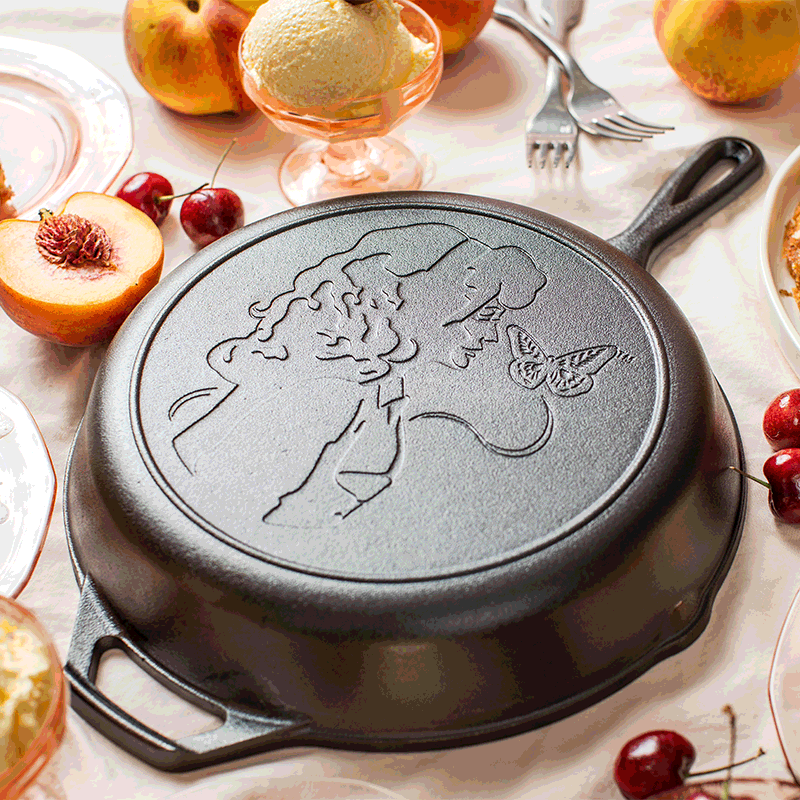 Cast iron skillet with embossed Dolly Parton profile and butterfly design, part of Lodge Cast Iron Kitchenware collection under $100
