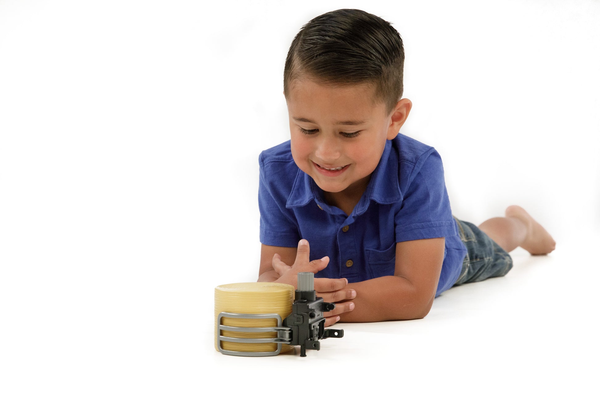 Young boy lying on floor playing with Bruder toy bale gripper and round bale in Toys & Games collection