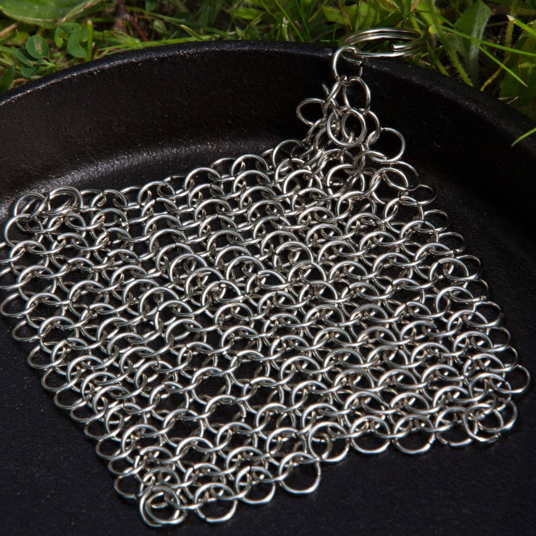 Square stainless steel chainmail cleaner resting inside black cast iron skillet in kitchenware under $50 collection