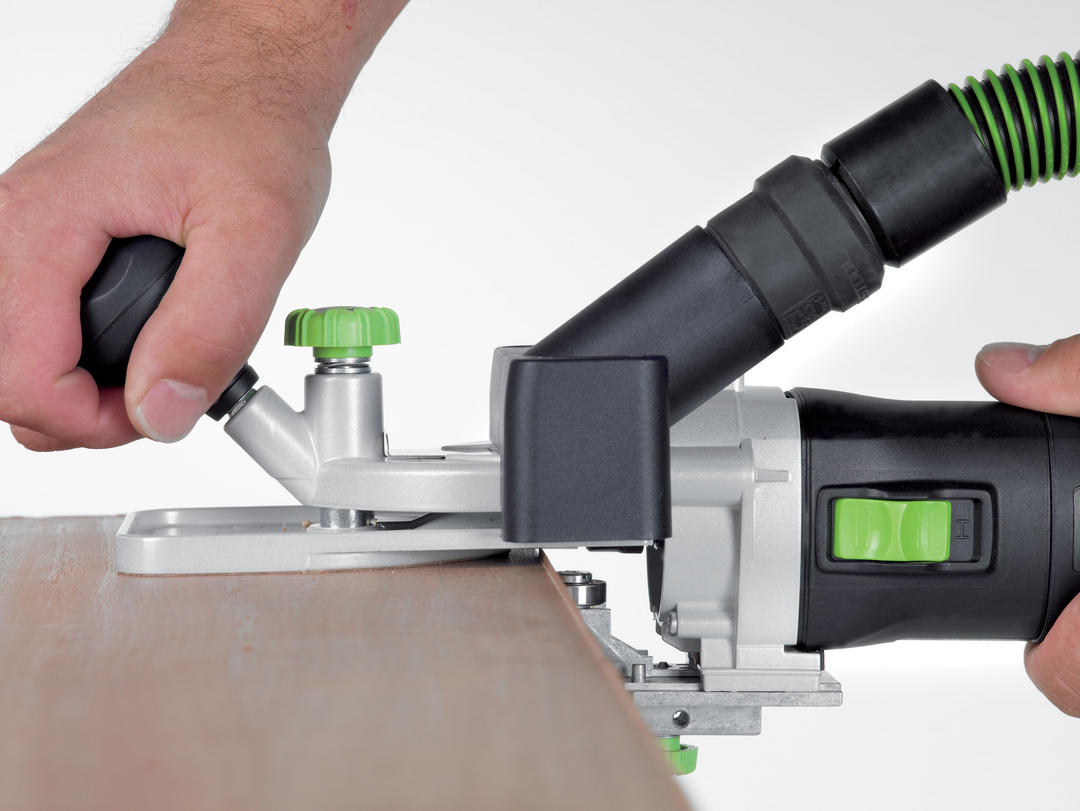 Close-up of a person operating a Festool 576239 MFK 700 EQ trim router with dust extraction for woodworking tasks
