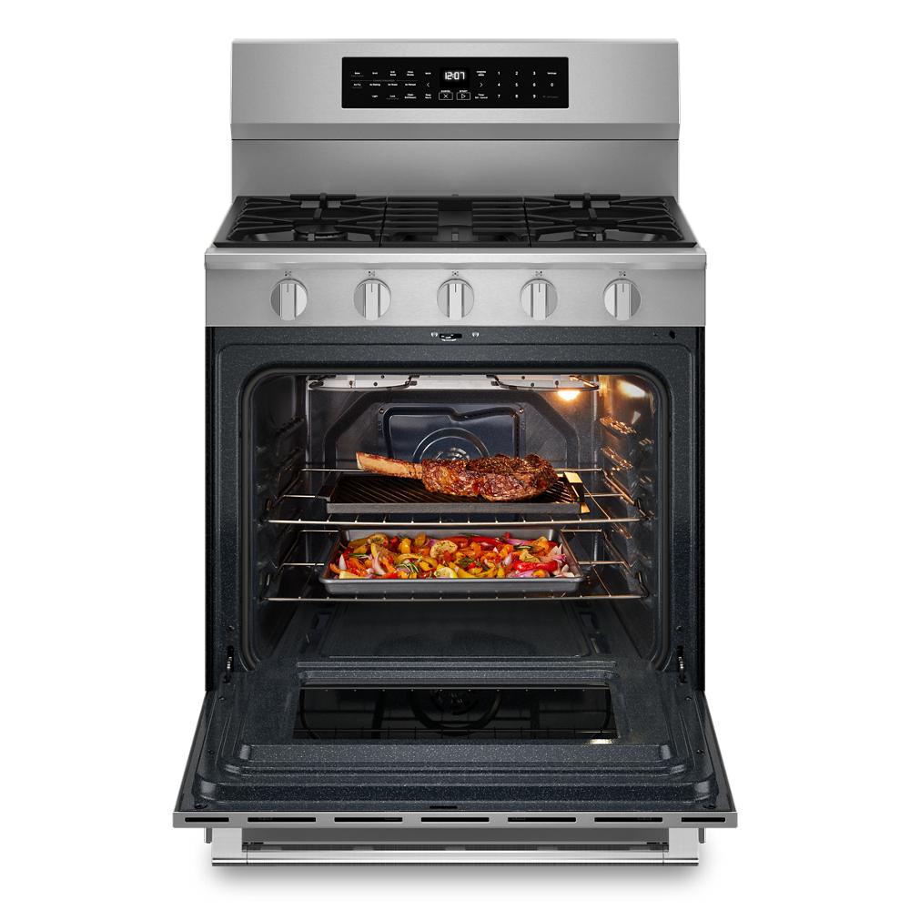 Stainless steel gas range with five burners and oven open showing steak and roasted vegetables inside from Ranges collection