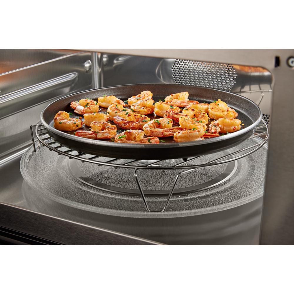 Grilled shrimp cooking on a round rack inside a stainless steel microwave combo wall oven cavity with convection feature