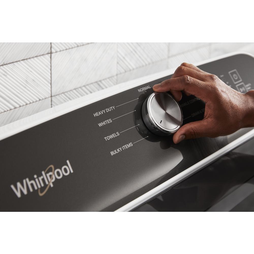Hand adjusting cycle selection knob on black control panel of Whirlpool gas dryer in appliances collection