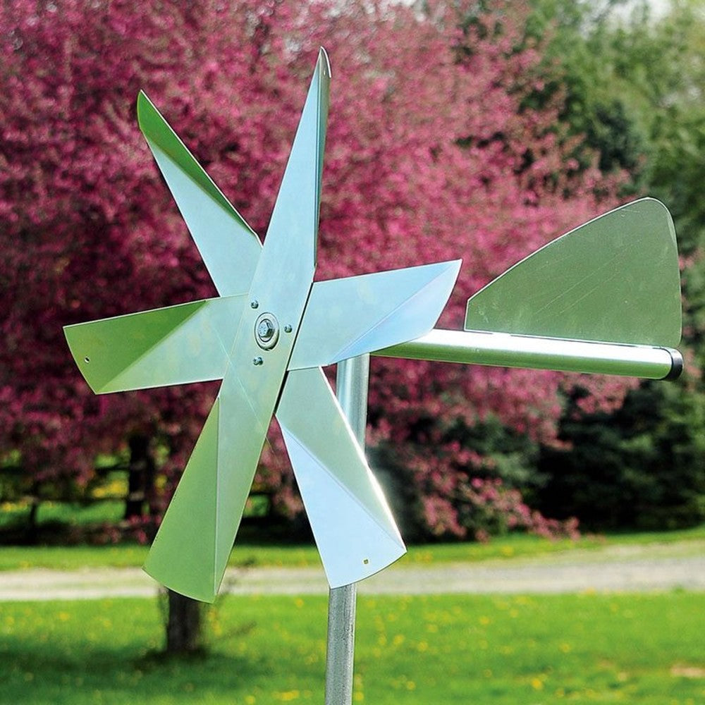 Metal outdoor windmill with multiple blades and a tail vane mounted in garden for pest control and lawn use