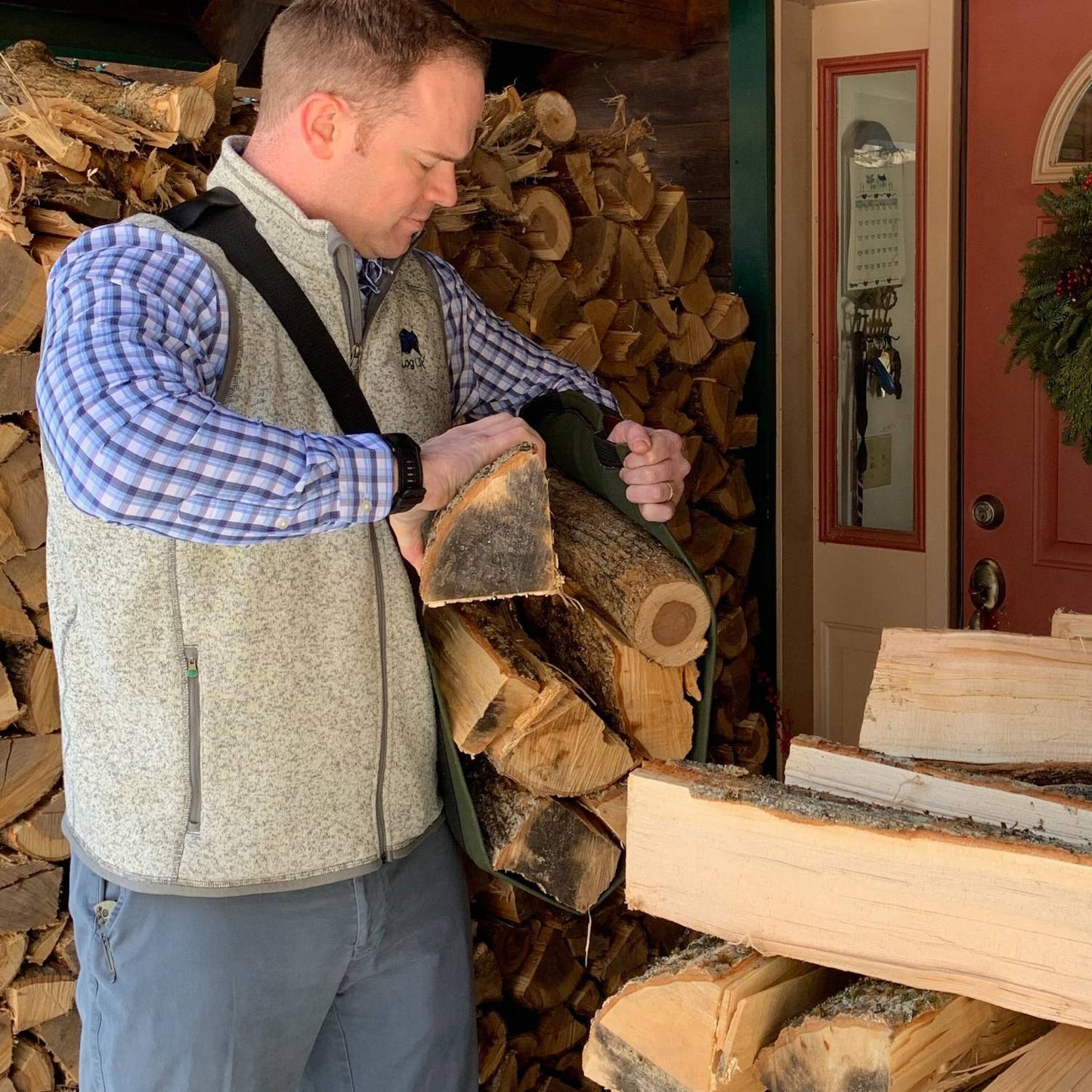 Man loading split firewood into green LogOX WoodOX sling firewood carrier for home improvement tasks